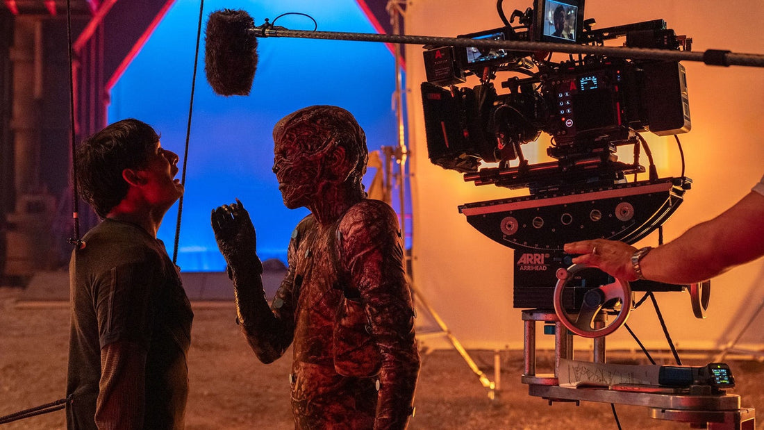 Plan de tournage de Stranger Things : caméra, perche son et fond bleu face à un acteur maquillé en créature
