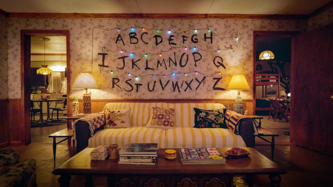 Le salon d'une maison de Hawkins : mur d'alphabet, guirlande allumée et canapé jaune des années 80