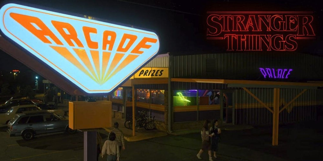 L'enseigne néon ARCADE du Palace allumée la nuit dans Stranger Things, des silhouettes devant l'entrée