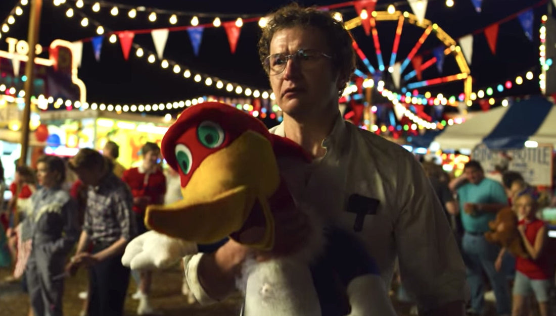 Alexeï à la fête foraine, un oiseau en peluche dans les bras, la grande roue derrière lui.