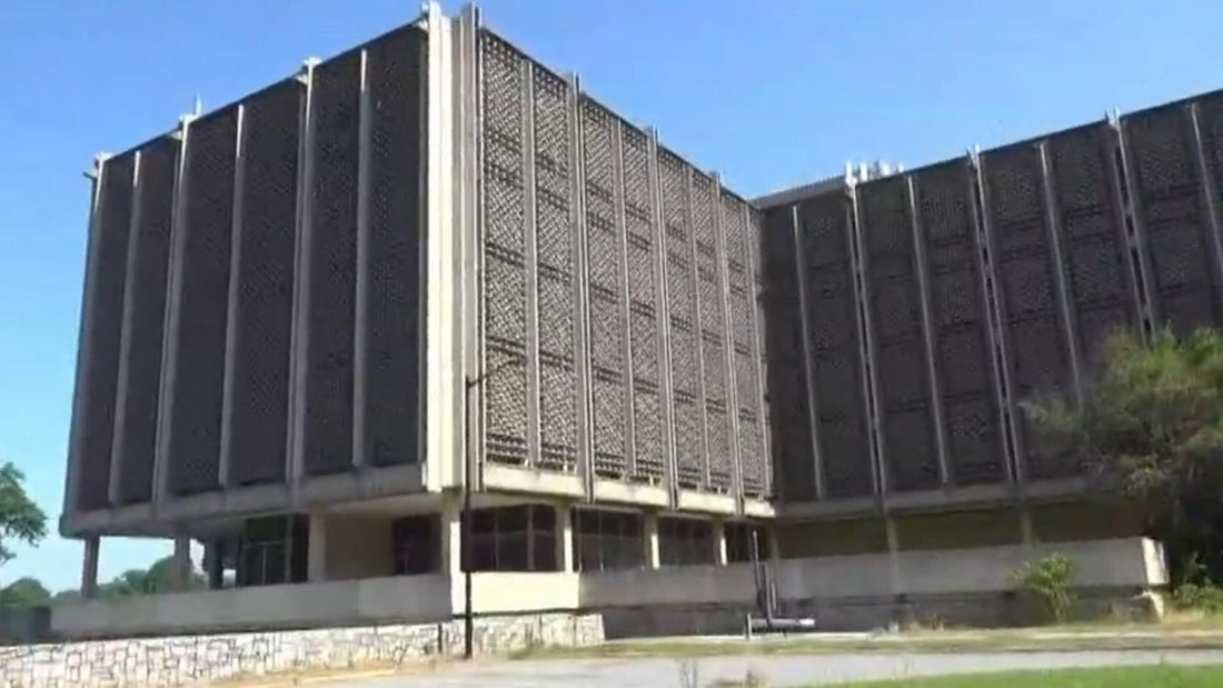 Grand bâtiment scolaire en béton, vu depuis la rue, sous un ciel bleu.