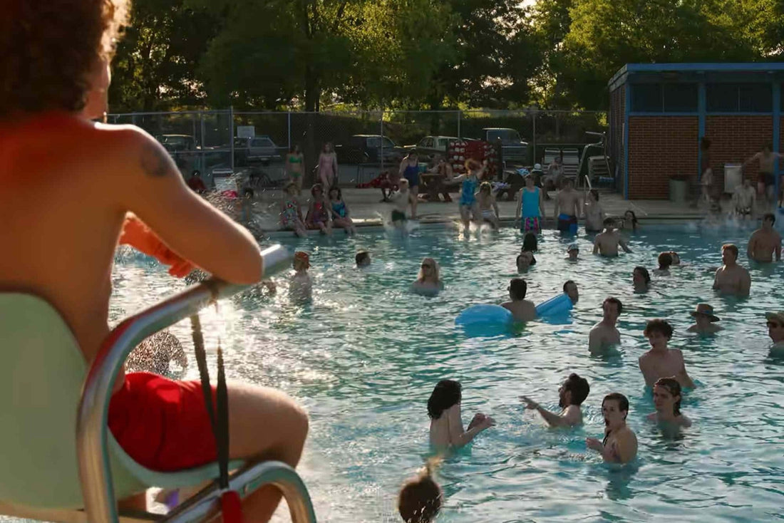 Bassin municipal bondé, l'été, siège de maître-nageur au premier plan.