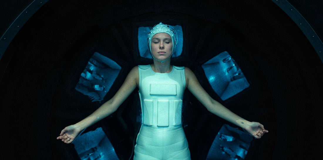 Onze dans la cuve, casque blanc et combinaison, des écrans autour d'elle.
