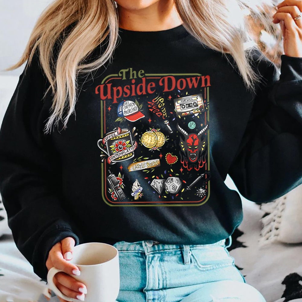 Sweat col rond Stranger Things The Upside Down objets cultes noir, objets de la série en tatouage rétro sur le devant